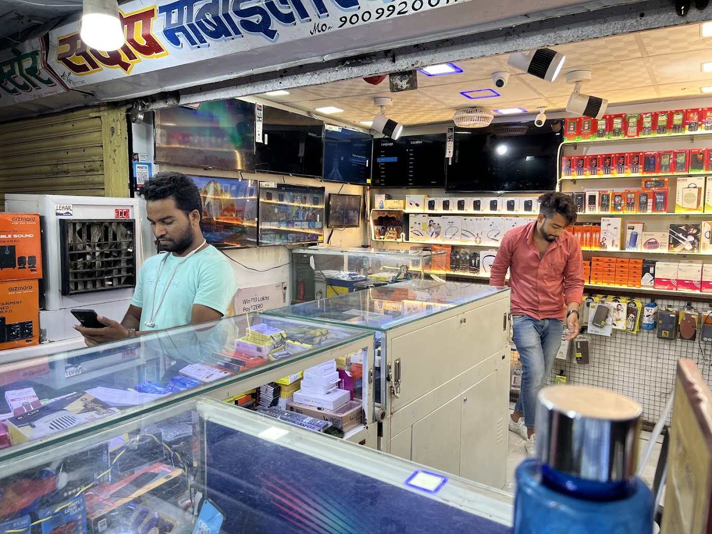 Inside Sandeep Mobile: glass counters of phones and accessories, TVs on the wall